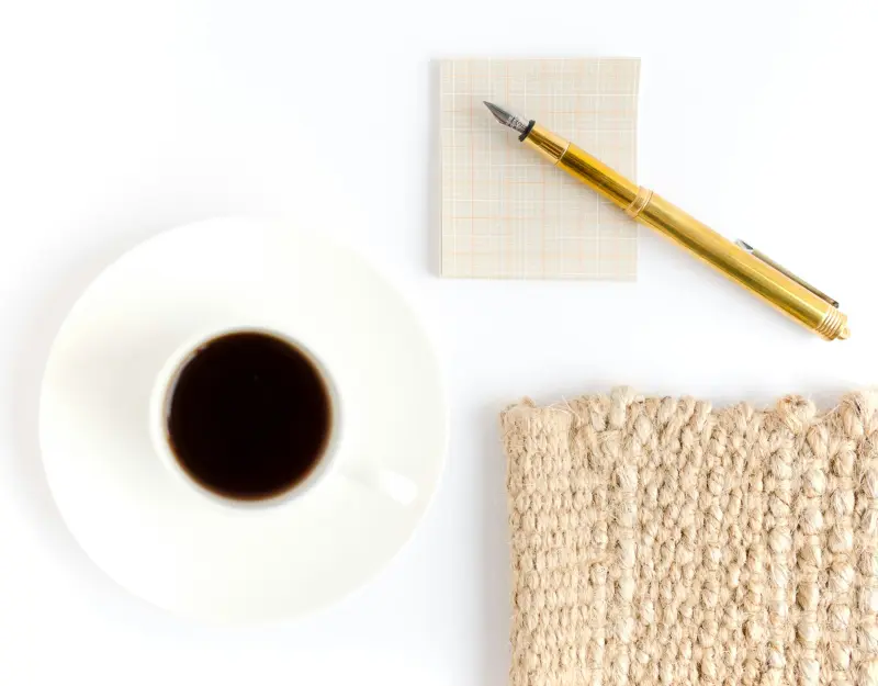 Service 3 A cup of black coffee, a gold fountain pen, and a woven mat.