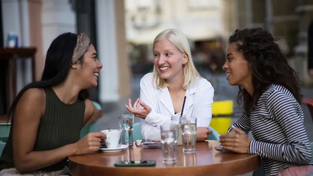 Three women chatting around a table.