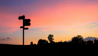 Signpost silhouettd against a sunset